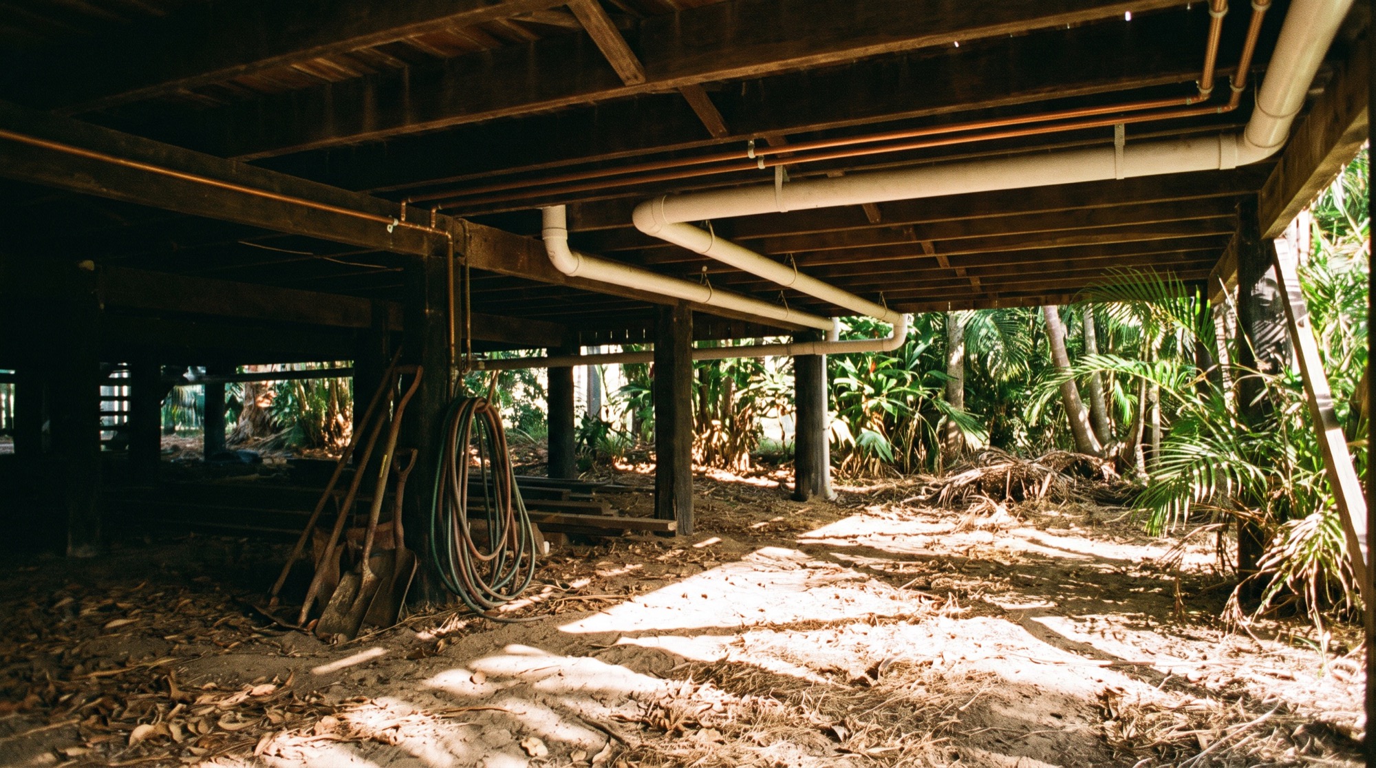 Drainage and copper pipework running under the floor of a raised timber house