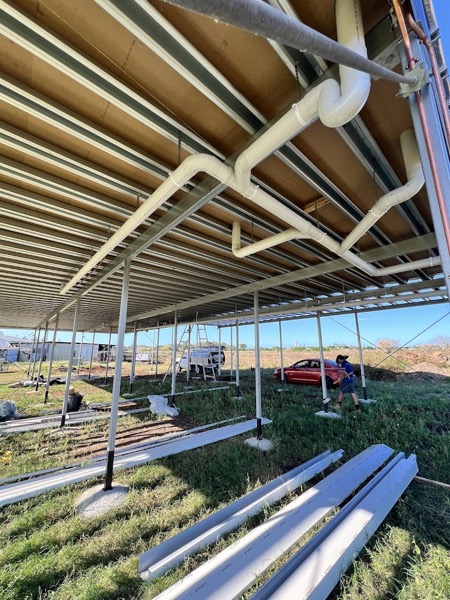 Sanitary and stormwater pipework running under a new steel-framed shed