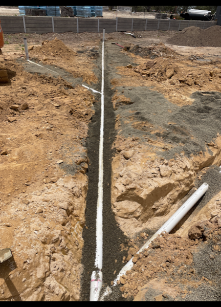 A long trench with a graded drainage line bedded in gravel
