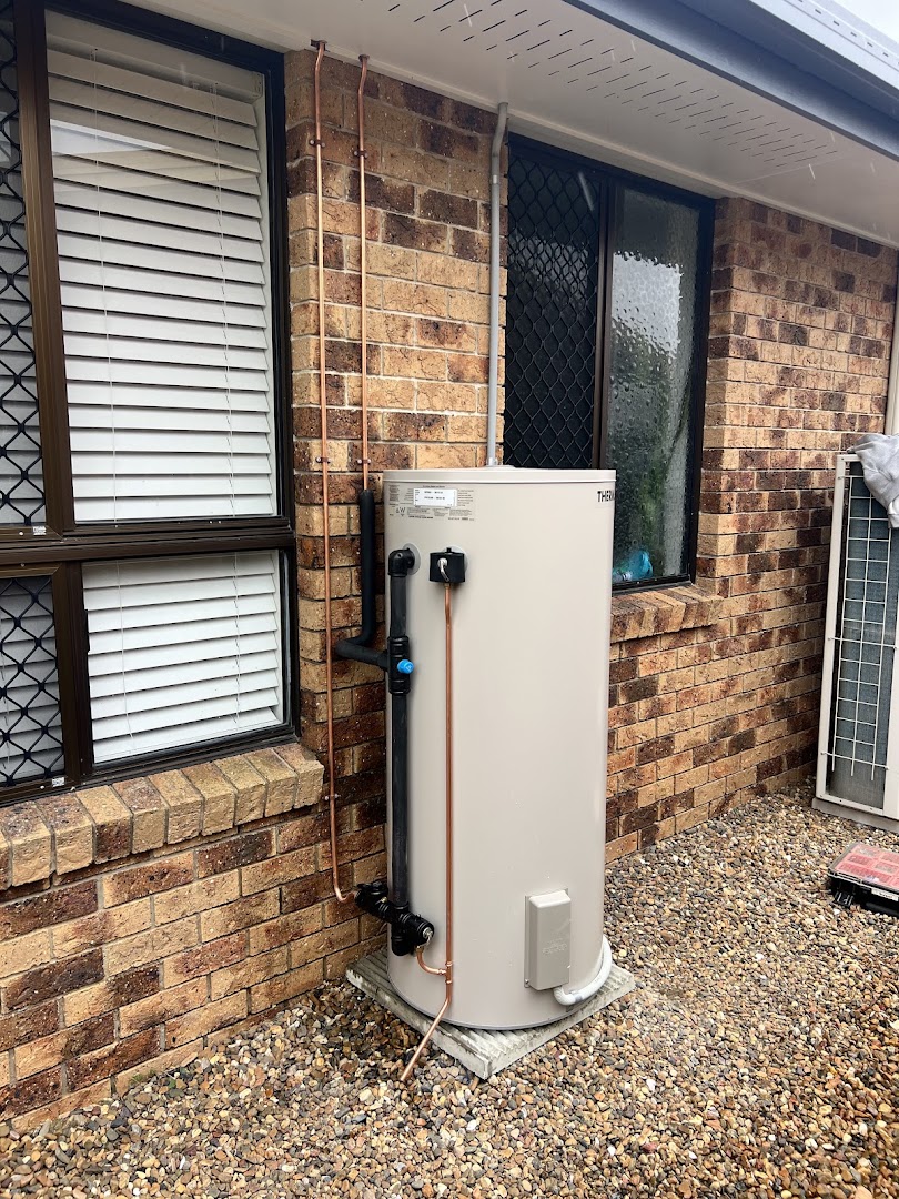 A storage hot water cylinder installed against a brick wall with new copper pipework