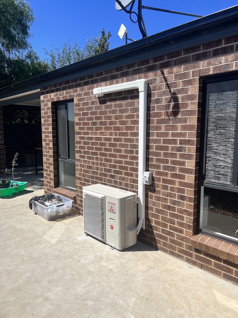 A split system air conditioning outdoor unit installed against a brick wall with new conduit